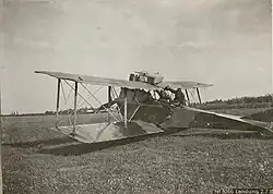Photo noir et blanc d'un avion biplan posé au sol.