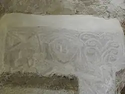 Personnage portant croix et feuillage.