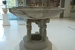 Grand bassin « dédalique » en marbre à piédestal, D. 1,24&nbsp;m, v. 675-650. Musée Arch. d'Isthmie (Corinthe)