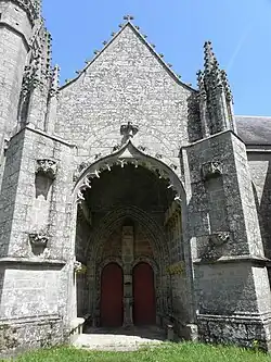 Entrée du porche vue de l'extérieur. Elle est encadrée de deux gros contreforts obliques.