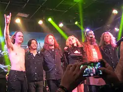 Six membres d'un groupe saluent son public en se faisant prendre en photo après un de leurs concerts