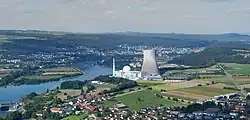 Au centre de la photo, on distingue la tour aéroréfrigérante, sur sa gauche le bâtiment du réacteur. Le Rhin coule sur la gauche de la photo le long du site de la centrale. Tout autour des champs et des maisons.