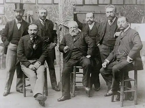 Professeurs de l'Académie Julian vers 1892 ; debout au second plan, de g. à dr. : Henri Gervex, Alfred-Henri Bramtot, Gabriel Ferrier (se tenant à une colonne) et Tony Robert-Fleury ; assis de g. à dr. : non identifié, William Bougereau et Jules Lefebvre.