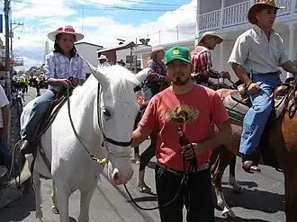Jeune cavalière vue de face et un homme tenant une boisson dans ses mains.