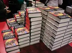 Plusieurs piles d'un même livre à la couverture noire, rouge et jaune, sur lequel est écrit « Harry Potter ».