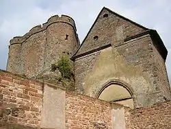 Vue sur la chapelle ainsi que les parties hautes du château comprenant deux tours reliées par un mur bouclier.