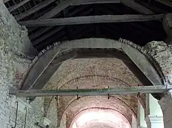 Photographie en couleurs d'un assemblage de pièces de bois supportant une voûte en briques.