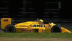 Photographie en couleur d'une Formule 1 jaune or, vue de profil droit, sur une piste.