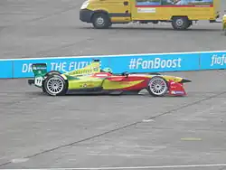 Photo vue de côté droit d'une monoplace jaune et rouge en piste