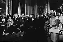 Photographie de Rosa Parks, Martin Luther King et d'autres membres du mouvement pour les droits civiques lors de la signature du Voting Rights Act de 1965 par Lyndon B. Johnson dans la rotonde du Capitole.