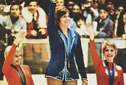 Photographie en couleurs montrant trois patineuses sur un podium saluant la foule.