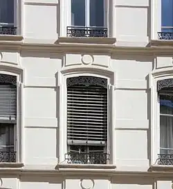 Une fenêtre lyonnaise avec un store appelé jalousie se déroulant à partir d'un lambrequin.