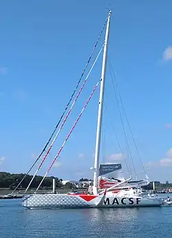 Voilier gris avançant au moteur, vu en entier, de profil.