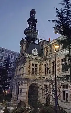 La mairie du 12e arrondissement de Paris, de nuit, avec un pompier sur le toit.