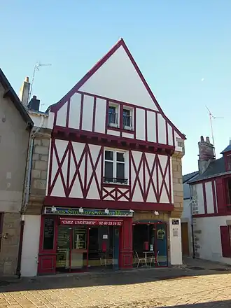 Vue d'une façade de maison blanche aux pans de bois rouges.