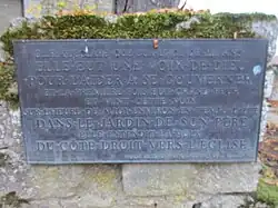 Plaque commémorative du jardin entre la maison et l'église, où Jeanne entend pour la première fois la voix de Dieu, puis celle des saintes Catherine d'Alexandrie, Marguerite d'Antioche, et de l'archange saint Michel.
