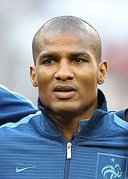 Photo de face de Florent Malouda avec une veste de l'équipe de France de football.