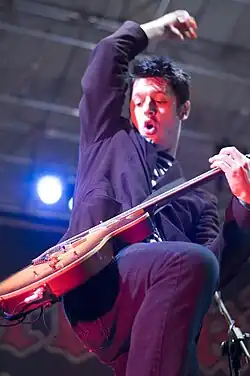 Homme caucaasien brun tenant une guitare.