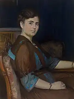 Halbfigürliches Portrait einer sitzenden Dame, den Kopf zum Betrachter gewandt, vor blauem Vorhanghintergrund, Louise Catherine Breslau, 1912.