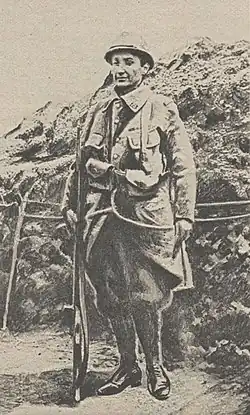 Une femme déguisée en poilu, arme à la main, dans les tranchées de la Première Guerre mondiale.
