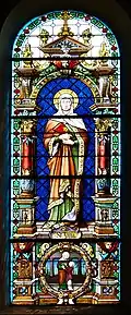 Photographie couleur d'un vitrail montrant une femme debout auréolée et les yeux clos.