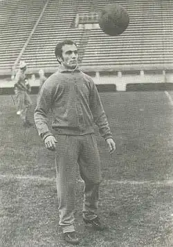 Photographie en noir et blanc d'un joueur de football de trois-quarts, s'entraînant avec un ballon.