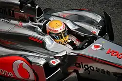 Baquet d'une monoplace gris argent, en gros plan avec le casque jaune de Hamilton.