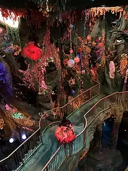 Un pont de verre serpente au milieu d'une forêt extraterrestre luxuriante.