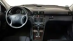 Photo du poste de conduite d'une voiture à sellerie en cuir noir, vue des places arrières.