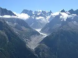 Vue contemporaine d'une vallée glaciaire avec son glacier largement recouvert de roches grises.