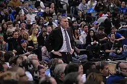 Mike D'Antoni, debout. Des spectateurs figurent au premier rang et en arrière plan.