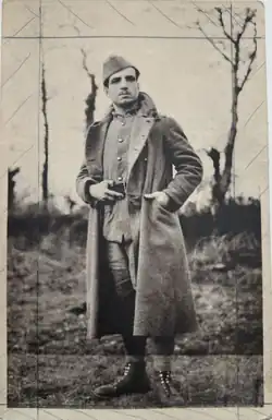 Photographie en noir et blanc d'un homme moustachu debout, vêtu d'un uniforme militaire.