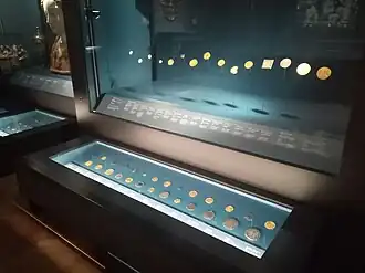 Monnaies ibériques (réaux, escudos), arabo-musulmanes (dinars) et grecques (drachmes) exposées dans des vitrines.