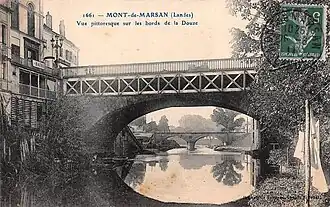Écriteau signalant la présence des bains publics au 1 rue Léon-Gambetta, au pied de l'actuel pont Gisèle-Halimi franchissant le Midou (et non la Douze comme écrit par erreur sur cette carte postale).