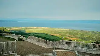 Un promontoire au-dessus de champs cultivés, avec vue sur la mer.