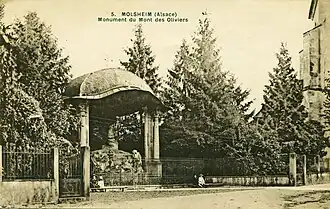 Carte postale ancienne montrant une sculpture entourée de conifères et abritée par un dôme.