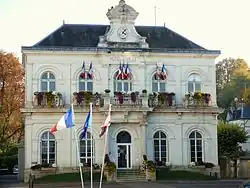 photographie d'un bâtiment à étages pavoisé de drapeaux tricolores.