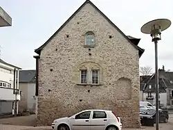 Photographie en couleurs d'une maison dont le pignon est percé de baies géminées.