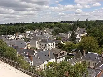 Photographie en couleurs de maisons dans une vallée au milieu d'arbres.