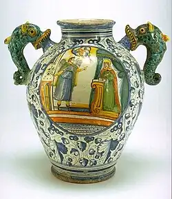 Vase ovoïde à anses en forme d'hippocampes ; l'Annonciation est peinte sur une face au centre d'un médaillon, de l'autre côté un cartouche médicinal, Montelupo Fiorentino, XVIe – XVIIe&nbsp;siècle.