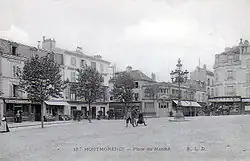 Carte postale noir et blanc : des enfants posent au centre ; autour, des maisons ; à droite, une calèche tirée par des chevaux.