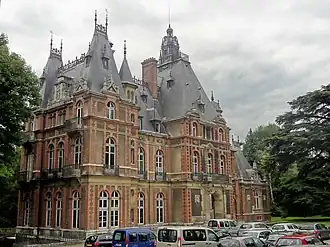 Façade d'un manoir à architecture complexe, aux murs gris à parement de briques rouges, richement orné, au toit en ardoise.
