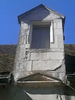 Vue de la lucarne d'une maison, ornée d'un écusson, d'un monogramme et d'une devise.