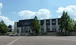Photographie en couleurs d'un vaste bâtiment récent portant en façade l'inscription « Hôtel de ville ».