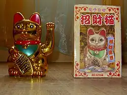 Un Maneki-neko doré électronique remuant la patte.