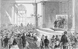 Gravure représentant un conférencier pointant un tableau représentant un gorille.