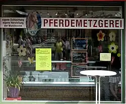 Devanture d'une boucherie avec une enseigne en forme de tete de cheval, suivie du mot "Pferdemetzger".