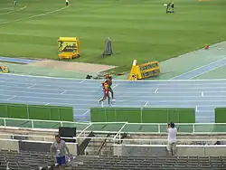 Deux athlètes en train de courir côte à côte sur une piste d'athlétisme.