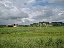 Bâtiment du MuséoParc Alésia dans la plaine des Laumes, au pied du village d'Alise-Sainte-Reine. À l'arrière-plan : le Mont-Auxois.