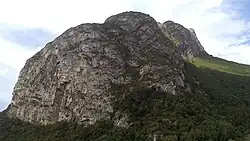 Crête d'une montagne vue en contre-plongée avec une grotte à sa base.